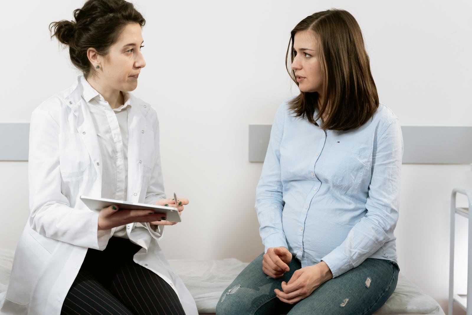 A doctor with a tablet talking with a patient seated on an examination bench