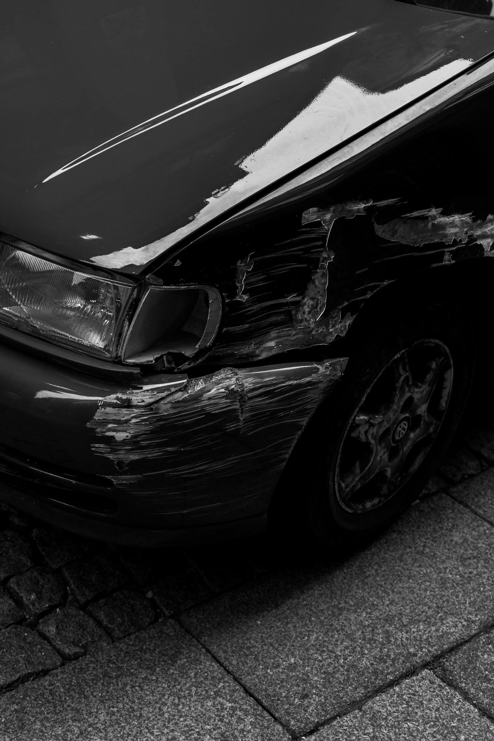 A deeply scraped and torn front guard on a parked car